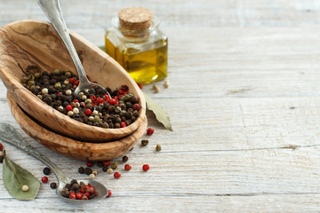 Fototapeta na wymiar Peppercorn mix in a bowl, bay leaves and olive oil