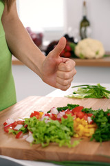 Close up of  woman's hands cooking in the kitchen. Housewife offering ​​fresh salad with thumbs up. Vegetarian and healthily cooking concept