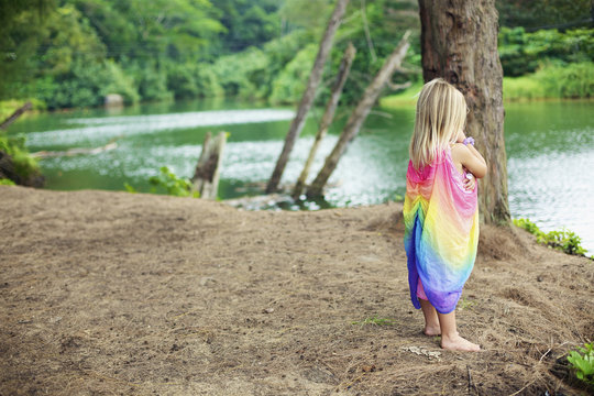 A young girl stands on the beach at the water's edge; Kauai, Hawaii, United States of America