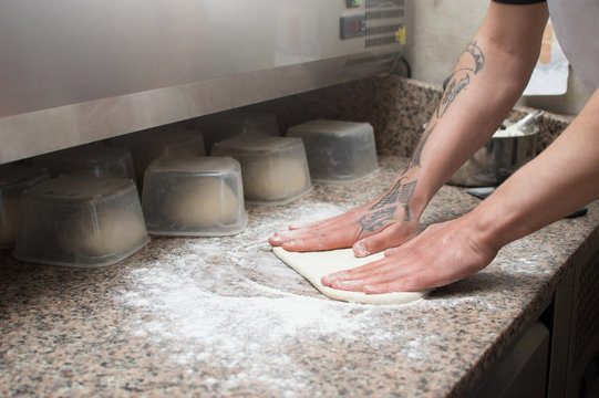 Close-up of male hands baker kneads raw pizza dough. Fast food. Pizza delivery.