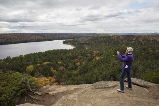 Woman takes pictures of Rock Lake from atop Booth's Rock, Algonquin Park; Ontario, Canada