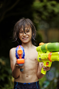 Young boy playing with water guns; Markham, Ontario, Canada