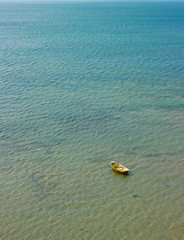 Wooden boat in shallow water. A large area of the sea surface and boat at anchor.