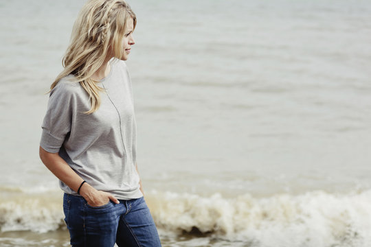 Portrait of a young woman with long blond hair at the ocean; Hastings, Sussex, England