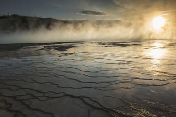Evening light shines through the steam rising over the Grand Prismatic Spring in Yellowstone National Park; Wyoming, United States of America