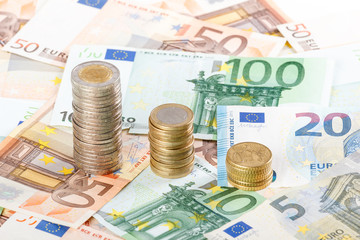 Euro coins stacked on euro banknotes background.