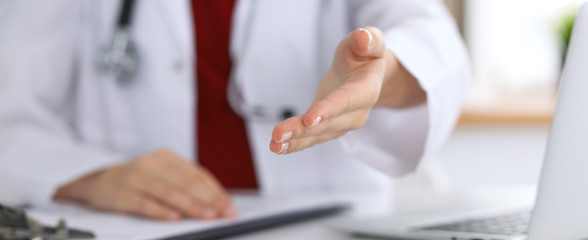 Female medicine doctor offering helping hand in office closeup. Physician ready to examine and save patient. Friendly and cheerful gesture. Medical cure and tests advertisement concept