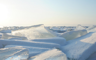 Early winter morning at Lake Baikal. rising sun colors the snow in shades of ultraviolet. Crystal clear transparent ice pieces refract sunlight.  Focus on the main central site. Photo toned.