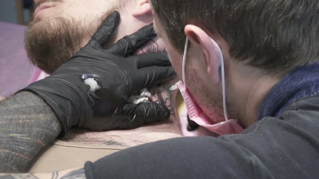 Closeup of creating tatoo of an animal on man's neck