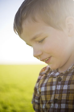 Young boy's profile with sunlight hitting his face in a farm field; Saskatchewan, Canada