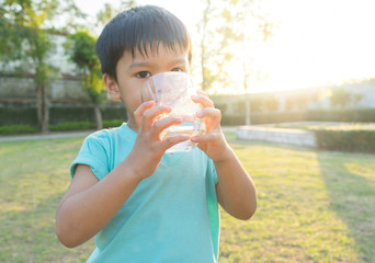 Asian boy drinks water with a glass in the garden