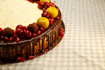 Triple chocolate cake decorated with pomegranate, cranberries and small apples.