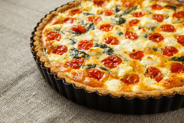 Vegetarian homemade pie, Quiche with tomatoes, spinach and feta cheese.