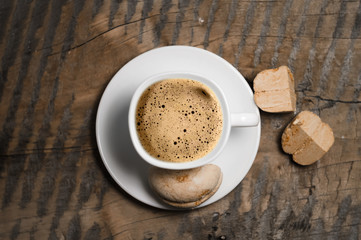 Coffee with foam and brown marshmallow on a wooden table