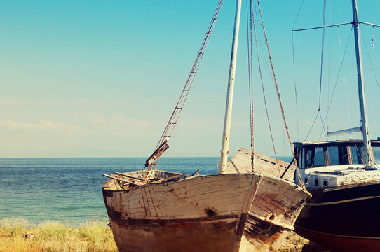Old abandoned boats on the beach against the sea on a sunny day
