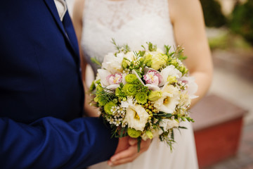 Obraz na płótnie Canvas Close up wedding bouquet at hands newlyweds.