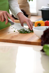 Closeup of human hands cooking vegetables salad in kitchen on the glass table with reflection. Healthy meal and vegetarian concept