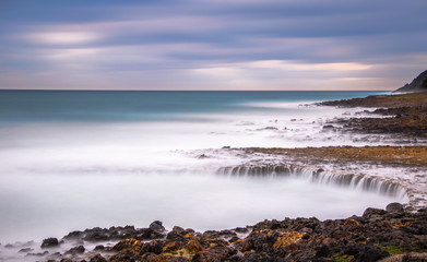Sea waves on a long exposure during sunset, with small waterfall, Crete, Greece
