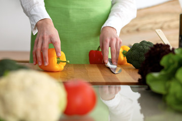 Closeup of human hands cooking vegetables salad in kitchen on the glassr table with reflection. Healthy meal and vegetarian concept
