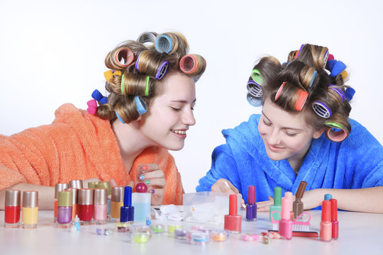 Beautiful girls with hair curlers on hair make manicure
