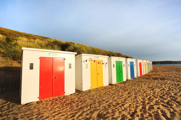 row of wooden painted brightly coloured beach huts