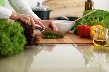 Closeup of human hands cooking vegetables salad in kitchen on the glassr table with reflection. Healthy meal and vegetarian concept