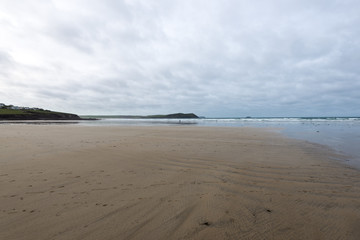 Expanse of beach leading to the sea with rock formations.