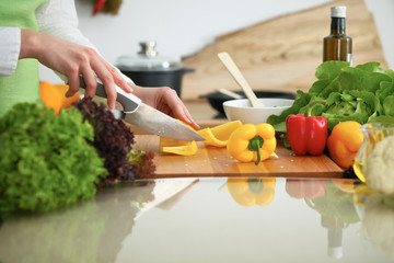 Closeup of human hands cooking vegetables salad in kitchen on the glassr table with reflection. Healthy meal and vegetarian concept