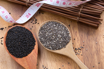 Chia seeds and Thai lemon basil seeds in wooden spoon on wood background with measuring tape