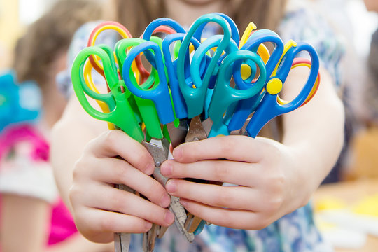 Children's Hands Holding The Scissors With Colored Plastic Handles