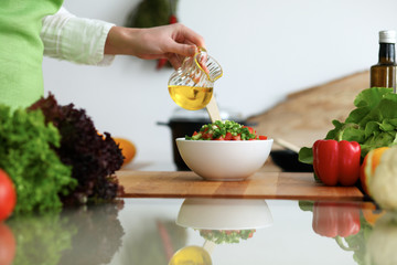 Closeup of human hands cooking vegetables salad in kitchen on the glassr table with reflection. Healthy meal and vegetarian concept