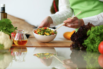 Closeup of human hands cooking vegetables salad in kitchen on the glassr table with reflection. Healthy meal and vegetarian concept