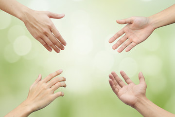 Naklejka premium four human hands try to reaching on blur natural green color background:collaborate working together concept:helping hands conceptual:renew and sustainability healing world together.