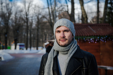 Handsome young man at the park in winter. He is looking forward. Blured background. He is froze.