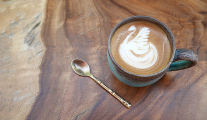 Top view of hot coffee latte art swan shape foam in ceramic cup on wood background
