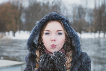 woman in a blue winter fur coat standing on the street in full growth