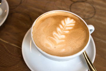 Latte art in a coffee milk on a wooden table.