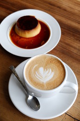 Coffee cup with latte art and pudding on the wood table