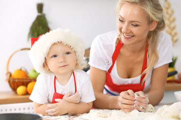 Happy family in the kitchen. Mother and child daughter cooking holiday pie or cookies for Mothers day, casual lifestyle photo series in real life interior