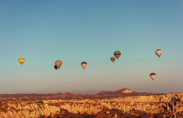 Hot air balloon flying over rock landscape at Cappadocia Turkey.