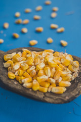 Grains of corn in a wooden spoon on blue background