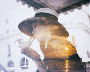 Double exposure of elegant woman drinking cocktail and lake sunset