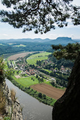 Fototapeta na wymiar A view from observation desk of Bastei in Saxon Switzerland, Germany to Kurort Rathen and the river Elbe on a summer day.