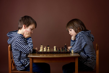 Little boys, playing chess. Smart kid, isolated, playing chess agains his brother