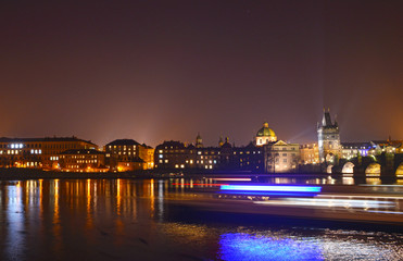 Fototapeta na wymiar Skyline Prag with a passing Boat by Night