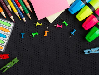 school supplies pencils, markers, buttons, colored paper on a black background