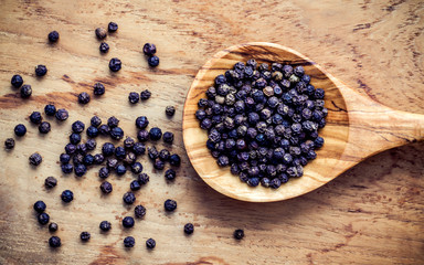 Closeup black pepper in wooden spoon on shabby teak wood table. Seasoning and species ingredients concept . Composition of black pepper for culinary ingredients.