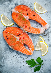 Fresh salmon fillet sliced flat lay on shabby metal background. Raw salmon fillet and ingredients parsley ,sweet basil leaves ,fennel ,pepper corn and lemon for cooking.