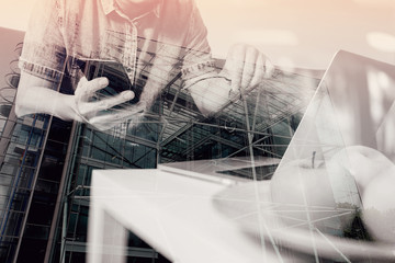 double exposure of hipster hand using laptop compter and mobile payments online business,eyeglasses,sitting on sofa in living room,green apples in wooden tray,London city buildings