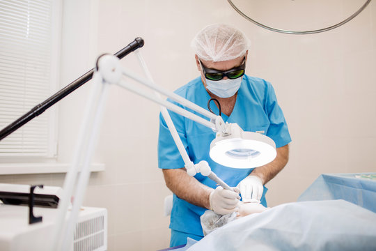 Doctor In Safety Glasses Using Laser For Facial Treatment In Cosmetology Clinic